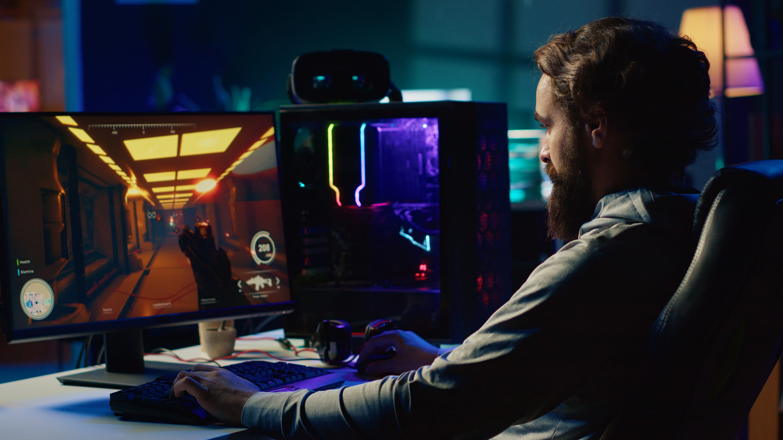 Client gaming at night on a dual-monitor setup with an ARGB tower